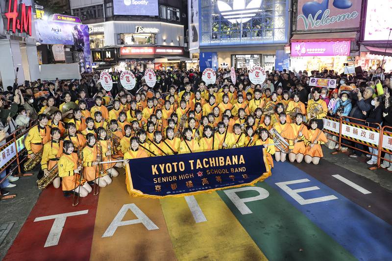 日本京都橘高校吹奏樂部18日再度應邀來台，晚間到訪台北西門徒步區快閃演出，有「橘色惡魔」之稱的團員們穿上橘黃色亮麗制服，在知名地標彩虹地景上留影