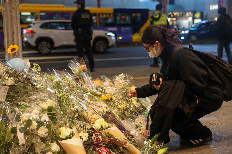 A woman leaves flowers for the victims of a Friday stabbing spree in front of the Eslite Spectrum Nanxi department store near MRT Zhongshan Station on Sunday. CNA photo Dec. 21, 2025