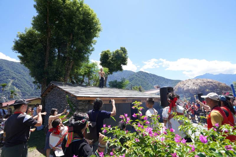 南投縣久美國小感恩祭的主祭者站在家屋屋頂進行拋酒糟儀式。