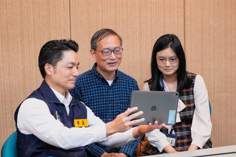 Taipei Mayor Chiang Wan-an (from left), doctor Yen Zui-shen and his daughter Yen Jun-jung look at a tablet conveying thanks from Taipei citizens. Photo courtesy of the Taipei City Government Dec. 21, 2025