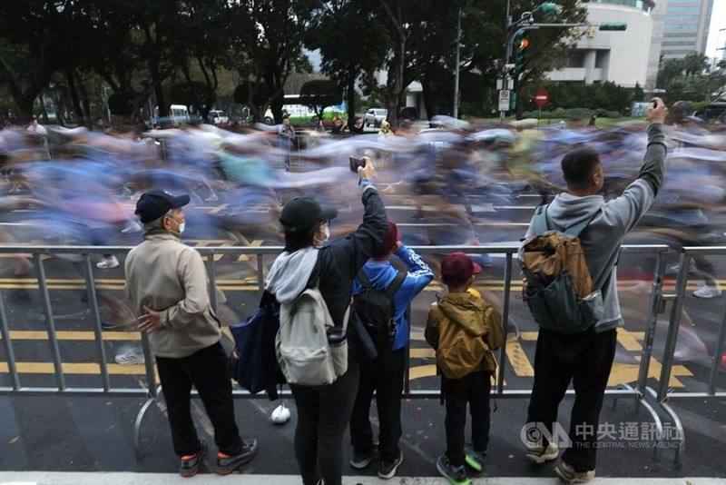 Bystanders look on and use cameras to record Taipei Marathon runners on Sunday. CNA photo Dec. 21, 2025