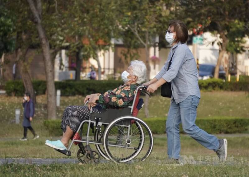 圖為民眾為長者推著輪椅到高雄市鳳山區公園內散心。（中央社檔案照片）
