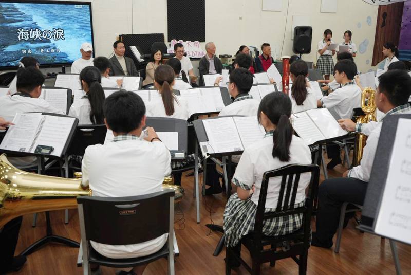 屏東縣大同高中管樂班學生26日歡迎日本學者井上裕太（後左4）等人來訪，現場演奏並合唱由井上裕太創作的歌曲「海峽之淚」，以音樂串起台日友誼。