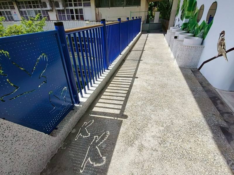 高雄市正興國小，新欄杆寶藍色鳥類鏤空造型沖孔板的倒影，結合廁所牆面的校園鳥類生