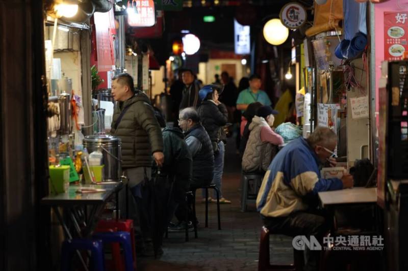 圖為新北市汐止區民眾穿著保暖衣物在外品嚐美食。（中央社檔案照片）
