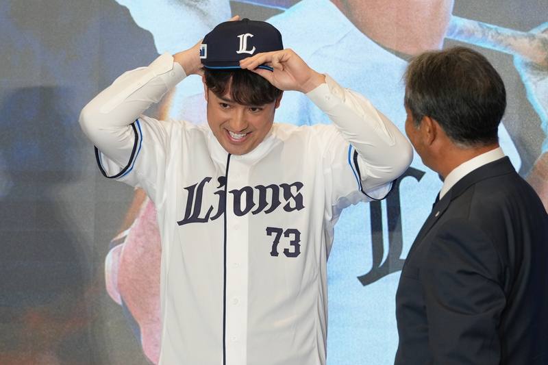 從中職統一7-ELEVEn獅隊轉戰日職埼玉西武獅隊的棒球好手林安可（左）9日在台北出席加盟記者會，現場穿上73號球衣、戴起新球帽