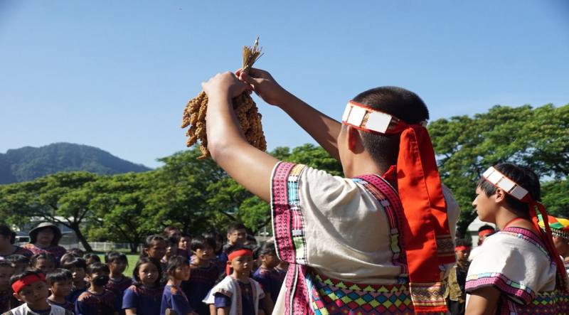 巴楠花部落國中小學生於「秋學祭－進倉祭」課程中，祝福小米。傳遞過程中必須高舉雙