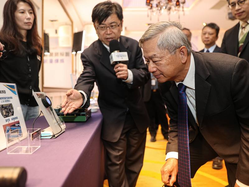 國科會主委、國研院董事長吳誠文（右）13日上午出席國研院半導體中心「晶片級先進封裝研發平台」發表記者會，聽取簡報時取下眼鏡近距離觀看展品