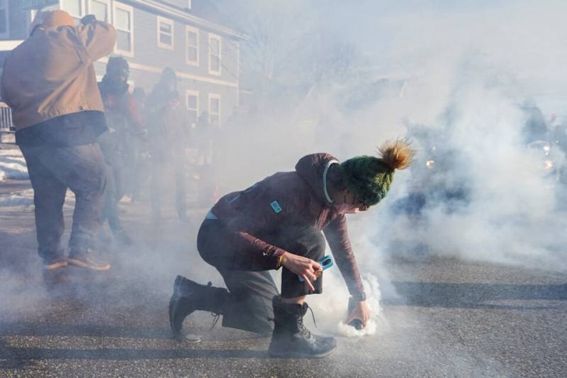 圖為美國明尼蘇達州13日的一場移民掃蕩行動，一名男子拿東西覆蓋住警方發射的催淚瓦斯。（路透社）