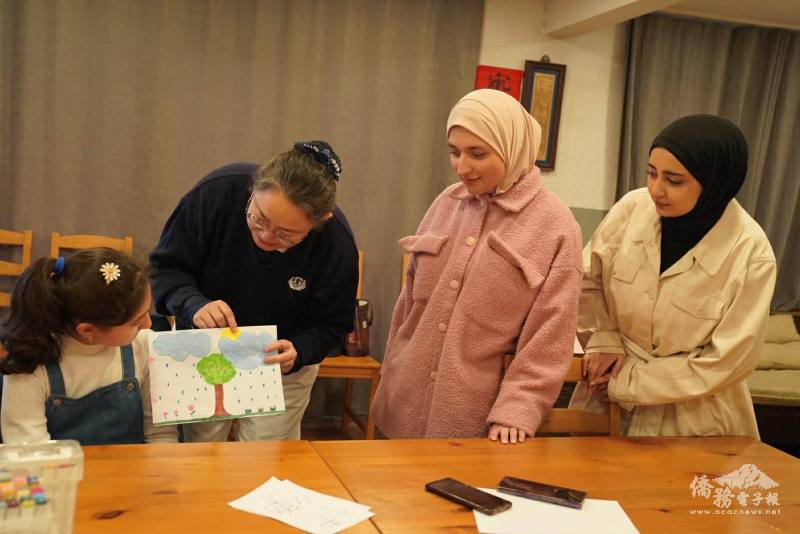 老師彎身指導作品，細心引導孩子說明作品內容，將語言學習自然融入創作之中