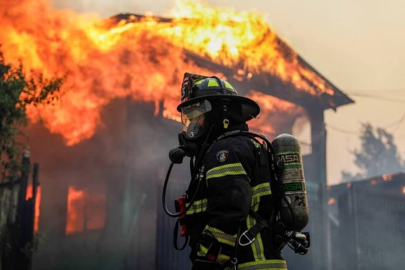 圖為智利消防隊員康塞普松站在一棟燃燒的建築物前。（路透社）