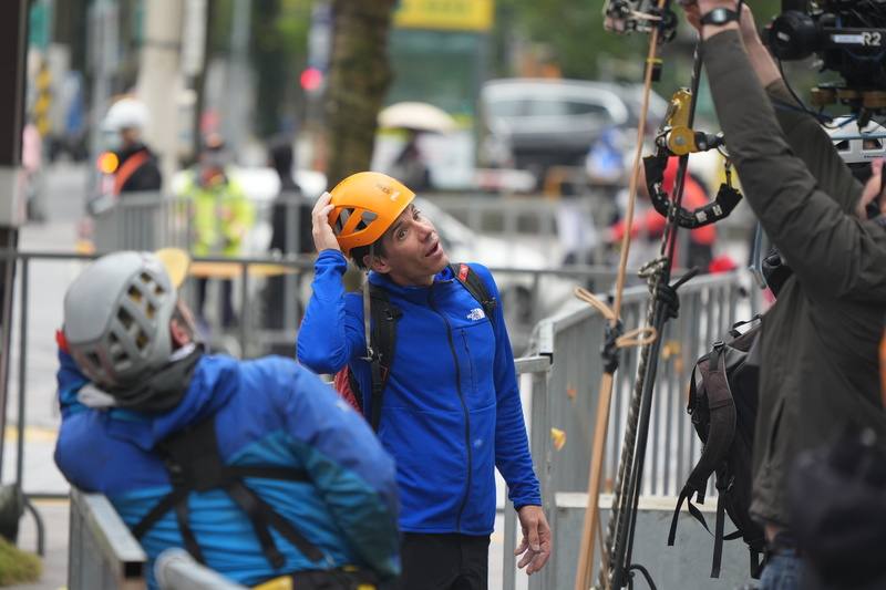 圖為霍諾德（中）21日進行雨天試爬前與團隊交換意見