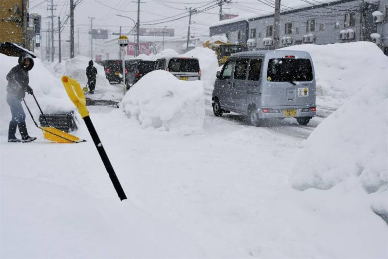 圖為日本青森縣居民2日清理街道上的積雪。（共同社）