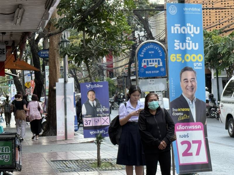 泰國曼谷街道掛有各黨總理及眾議員候選人看板。圖為民眾在選舉看板旁的公車站等車。中央社記者李宗憲曼谷攝