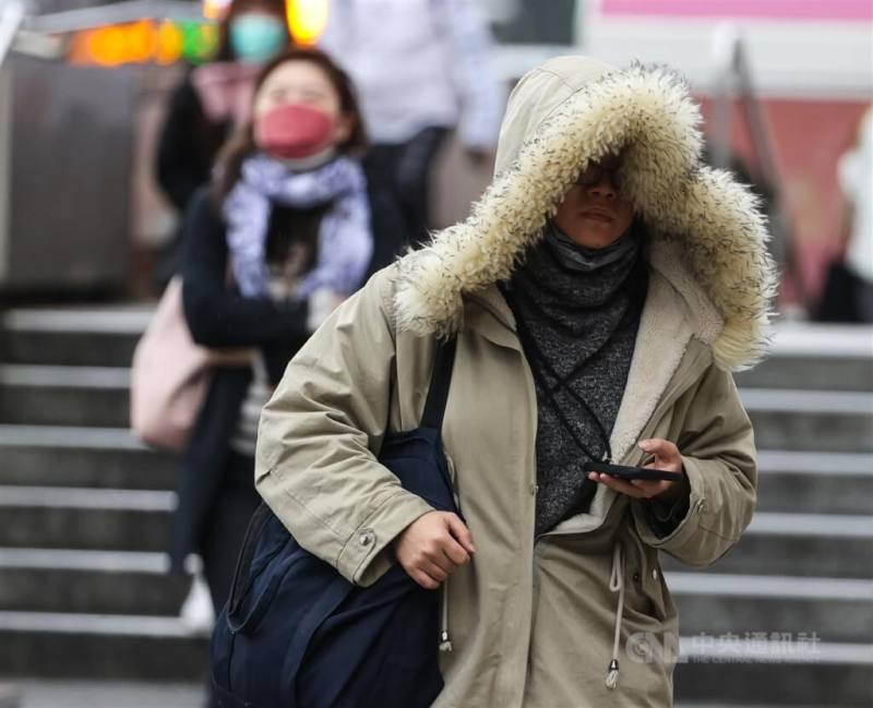 圖為台北市中正區民眾穿上厚外套、戴帽子禦寒。（中央社檔案照片）