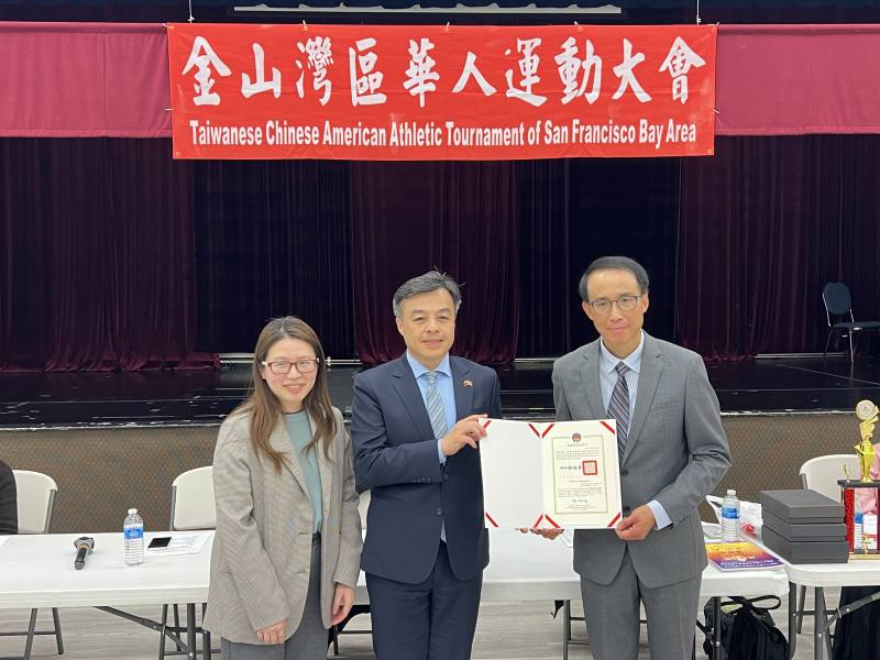 伍志翔(中)代頒僑務委員會賀狀給連任主任委員陳立功(右)並由蔡佳樺(左)宣讀。