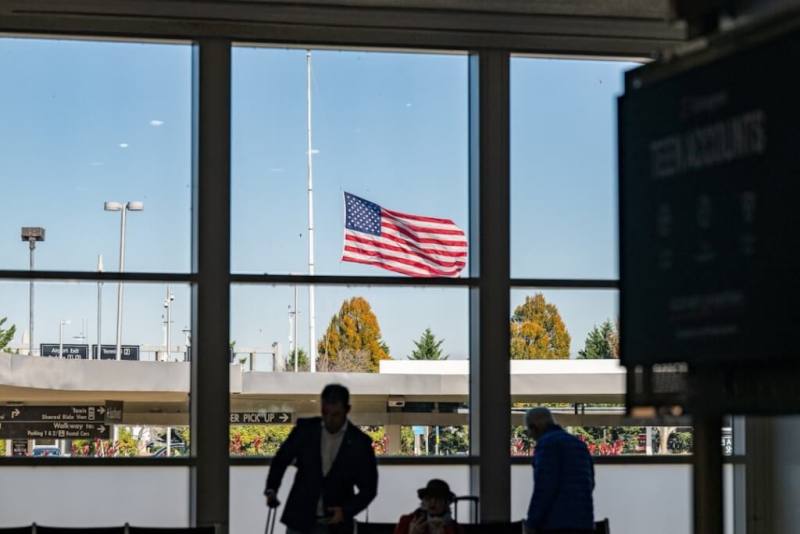 乘客在華盛頓機場候機時，一面美國國旗在外飄揚。（路透社）