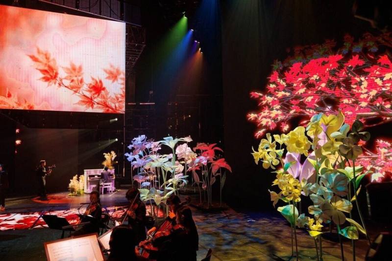 春節節目「2026 WE ARE 我們的除夕夜」中，將有歌手Bii畢書盡、黃偉晉Wayne、Ray黃霆睿、邱鋒澤帶來「島嶼四季交響」主題，舞台由巨型花藝紙雕作為背景。（中華文化總會提供）