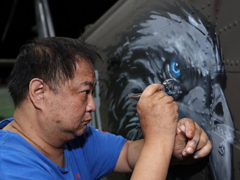 模型職人樊成彬（圖）義務投身國軍黑鷹直升機彩繪。圖為利用製作模型的小噴槍，細膩雕琢鷹眼紋路。（傅心銘提供）