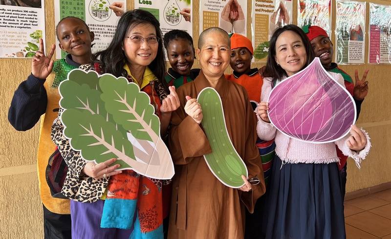 南非佛光山南華寺新春期間舉辦蔬食品嘗會，覺諦法師（前排中）與當地青年手持蔬菜造型道具合影，倡議蔬食永續與愛護生命理念。中央社記者李依璇布朗浩斯普特攝