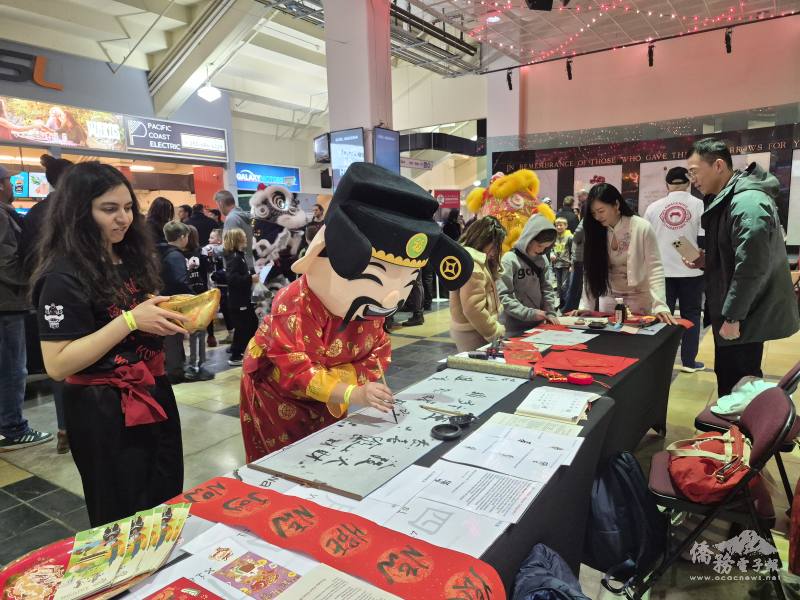 財神爺駐足同鄉會攤位前揮毫寫春聯