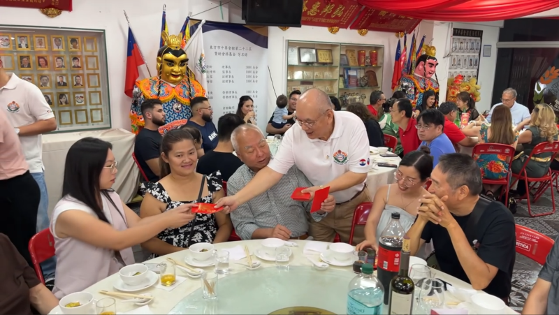 向在場來賓分送新年紅包象徵平安與好運