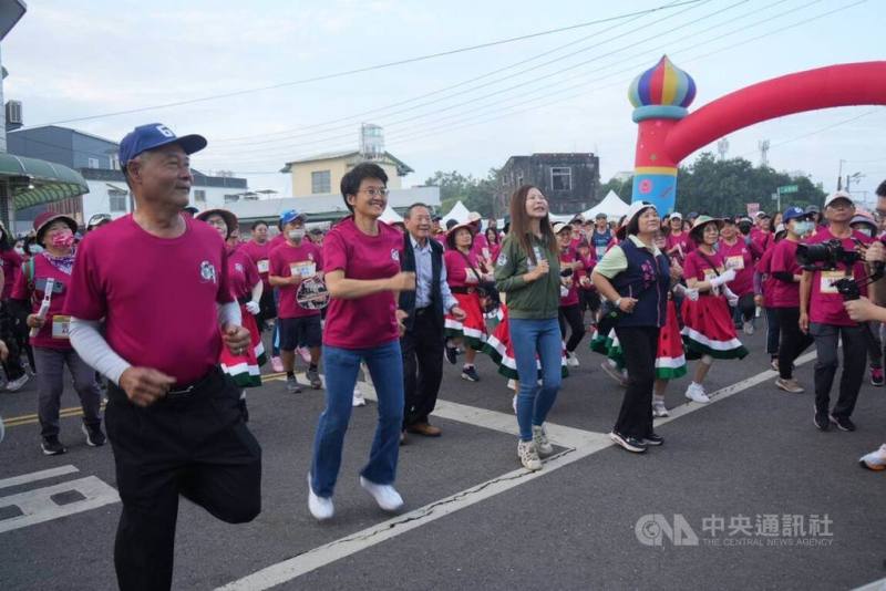 六堆健行路跑活動1日在屏東縣佳冬鄉登場，客委會主委古秀妃（前左2）、佳冬鄉長賴文一（前左1）及多名在地民代，一早在佳冬鄉公所前率跑者跳熱身操