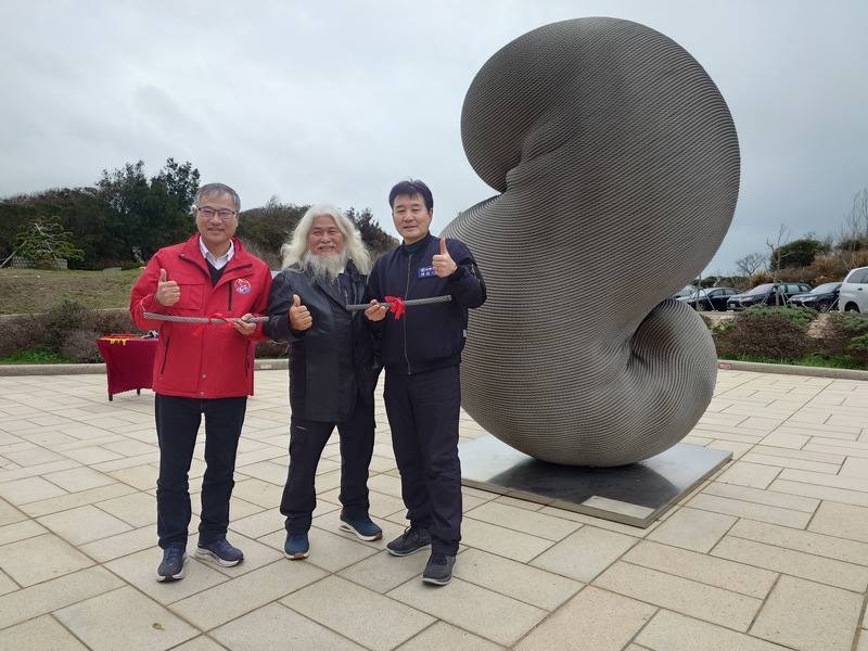 藝術家康木祥（中）推出鋼纜作品離島巡迴展，最終站落腳馬祖。馬祖國家風景區管理處5日舉辦揭幕儀式，包含連江縣副縣長陳冠人（右）、南竿鄉長林志東（左）等人出席，與康木祥一同在作品前合影。中央社記者潘欣彤攝