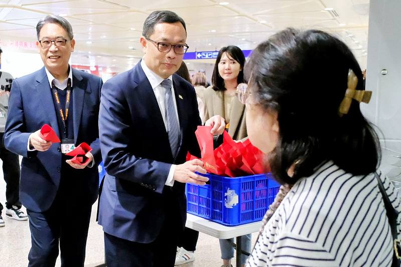 美伊開戰後，第2架從杜拜返台班機5日下午飛抵桃園機場，外交部政務次長陳明祺（左2）等人接機，分送蘋果酥給平安返台民眾。中央社記者吳睿騏桃園機場攝