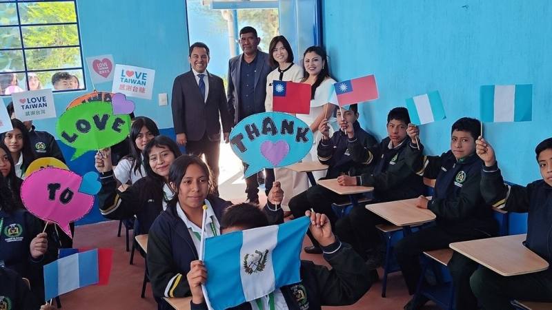 台糖小農咖啡助建瓜地馬拉第2間偏鄉教室正式啟用，當地學子在新教室手舉標語及國旗表達感謝。（台糖提供）