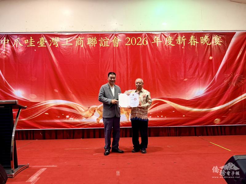 中爪哇台商會春酒中，安排僑務諮詢委員彭春源(左)頒發賀狀予續任理事長黃媽易(右)