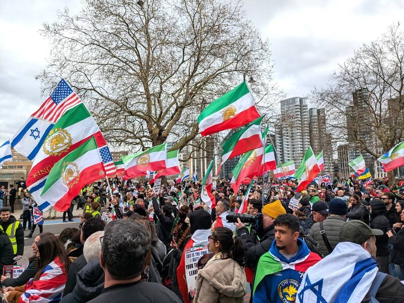 旅英伊朗人、以色列人等數百民眾15日在倫敦市中心泰晤士河北岸集會，支持美國和以色列對伊朗發起的軍事行動。現場可見遭德黑蘭當局嚴禁的伊朗「獅子與太陽」旗，象徵1979年伊斯蘭革命以前的伊朗。