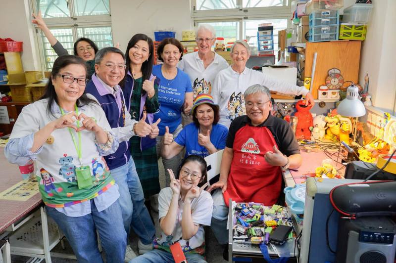 澳洲玩具圖書館總會18日參訪新北玩具銀行，雙方交流玩具的材質和回收再利用等議題。台灣玩具圖書館協會理事長余良玲（前左1）與訪團成員、玩具醫師等合影。（新北市府社會局提供）