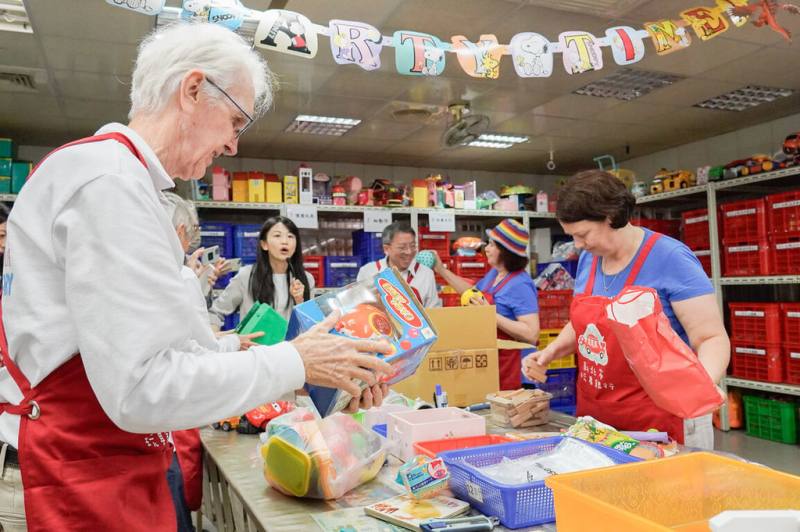 澳洲玩具圖書館總會18日訪問新北市玩具銀行，交流玩具材質與回收再利用。澳洲參訪團穿起玩具銀行紅色的志工服，一起體驗回收、分類和整理。（新北市府社會局提供）