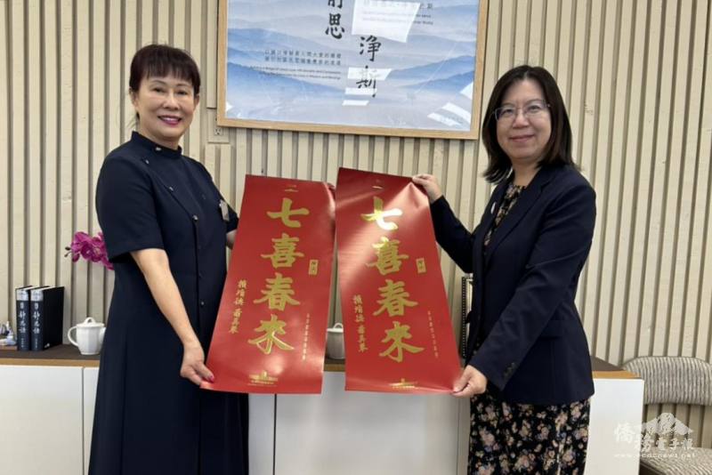 鍾佩珍（右）與僑務諮詢委員黃玉蓮（左）向當地僑胞介紹「七喜春來」春聯。