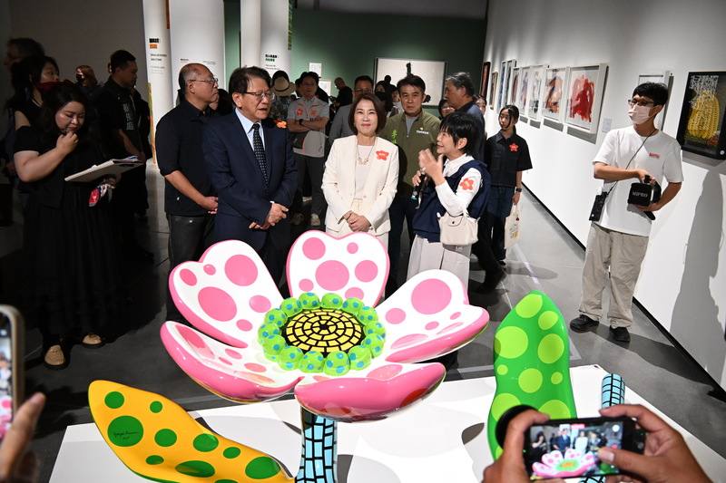屏東縣立美術館27日開幕，總統府祕書長潘孟安（前左）、屏東縣長周春米（前中）等人，一起欣賞日本藝術家草間彌生作品「花朵正在綻放」。