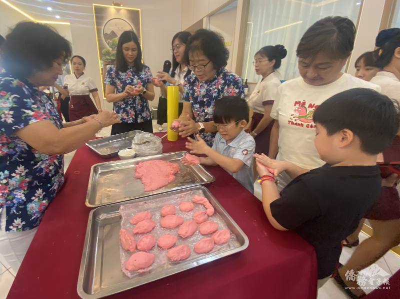 越南客家鄉親與小朋友大手拉小手，共同揉製象徵傳統滋味的手作客家菜包，場面溫馨