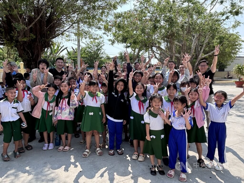 胡志明市台灣商會成員受邀參訪越南新祿島上一座國小，成員受到學童熱情歡迎、包圍，被天真笑容感染。