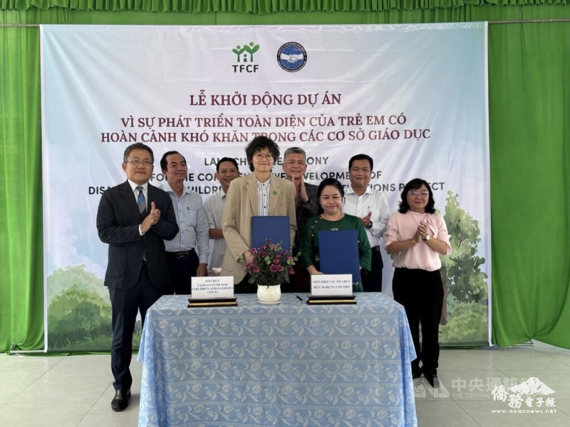 芹苴市越南友好組織主席黎氏成江（前右）與家扶基金會越南代表黃雅歌（前左）3月31日於新祿島上國小簽署合作備忘錄。駐越南代表劉世忠（後排左1）、胡志明市台商會長曾潮星（後排右3）等人見證。