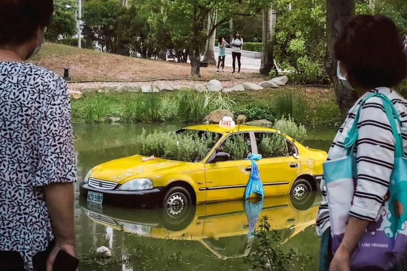 高雄市立美術館園區因一輛計程車泡在湖面上引發虛驚。高美館表示，這是台電公共藝術祭「奧拉之城III－未來已讀」展件之一，展覽4月3日登場，展期至6月7日。（高美館提供）