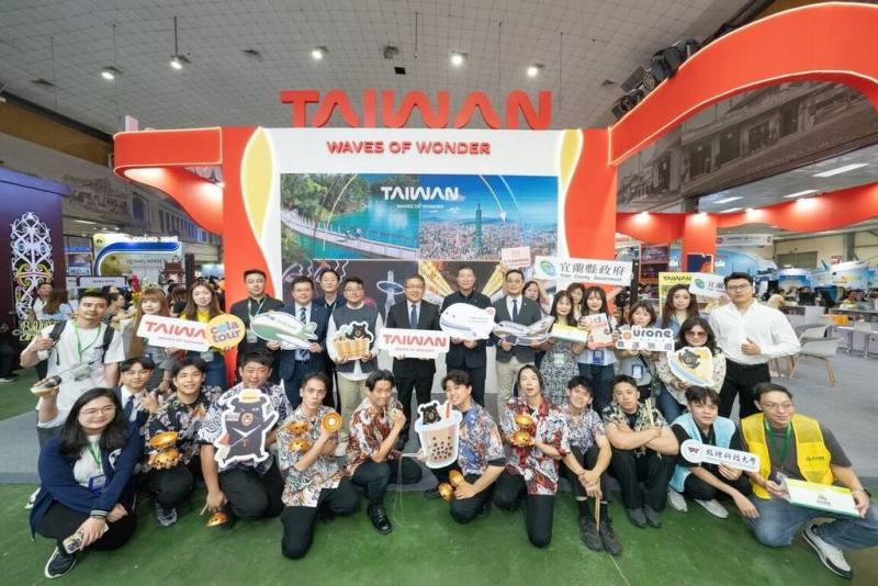 駐越南代表劉世忠（後中著西裝者）10日參訪河內國際旅展台灣館，與台灣觀光業者、台灣表演者，以及越南觀光機構代表等人合影。他向越南媒體表示，台越人民互訪熱絡，台越觀光旅遊合作商機無限。（觀光署提供）