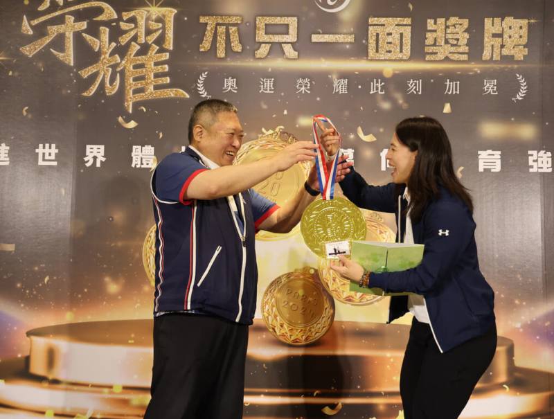 「舉重女神」郭婞淳（右）在東京奧運拿下金牌，13日獲宏道基金會頒發新台幣1000萬元獎金，她也回贈宏道基金會董事長林鴻道（左）一面自己手作的大金牌。