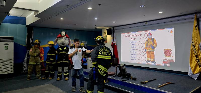 菲華文經總會消防研習營同學會財政主任蔡志堯向小朋友們簡單介紹消防員裝備
