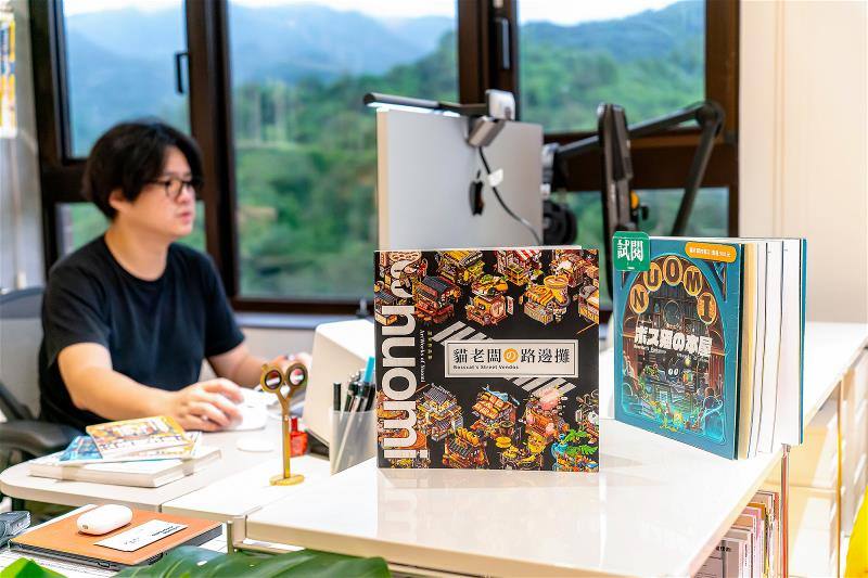 擅長畫建築，卻坦言不擅長畫人的諾米，設計出了場景中的吉祥物「貓老闆」，他也以貓老闆為主題，畫了幾本畫冊。（林旻萱攝）Though Nuomi doesn’t specialize in human figures, he has created a mascot called Boss Cat to enliven his street scenes. Boss Cat also features in his picture books. (photo by Lin Min-hsuan)​​