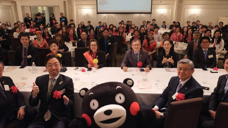 台灣國際美食創新交流協會17日在熊本台日會館舉行熊本分會成立大會，人氣吉祥物熊本熊到場站台。熊本縣知事木村敬（前排左1）、駐日代表處農業組組長王清要（第2排左4）、協會總會長何淑子（第2排左2），以及熊本分會會長錢妙玲（第2排左3）與會。（熊本分會提供）