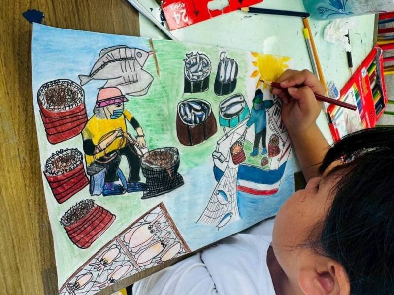 澎湖風櫃國小學生顏芷葳細膩描繪在地漁村生活，將在烈日下整理漁網、曬小管，以及漁民出海捕魚的辛勞景象生動呈現，於第21屆「我的家園」國際繪畫比賽，奪得三等獎。（澎湖縣政府提供）