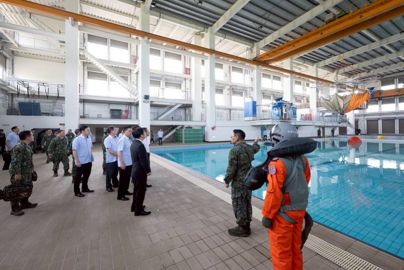 總統首先抵達「飛訓部國軍空勤人員求生訓練中心」，聽取任務簡報，並至訓練棚場視導傘拖、傘罩、直升機吊掛演練及水下棄艙逃生訓練