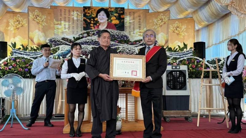 首頁 / 文化
「台東藺草編」保存者林黃嬌辭世　文化部頒旌揚狀
2026/4/23 11:00（4/23 11:31 更新）
台東縣傳統工藝「台東藺草編」保存者林黃嬌13日辭世，享壽95歲。文化部文化資產局長陳濟民（右）23日出席告別式，並頒贈文化部旌揚狀，由林黃嬌之子林瑞庭（左）代表受贈。（文化部文化資產局提供）