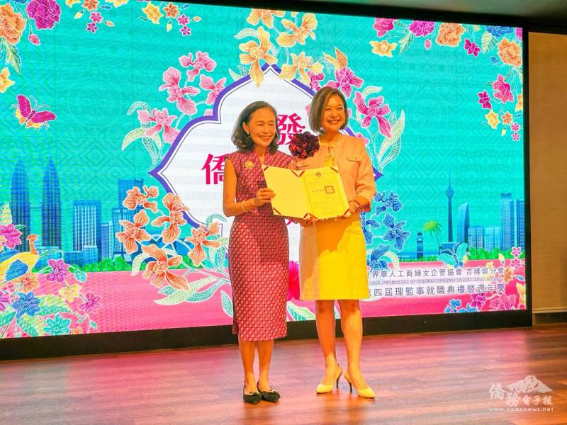 連玉蘋(左)代表僑務委員會委員長徐佳青頒發賀狀予會長廖妙溶(右)