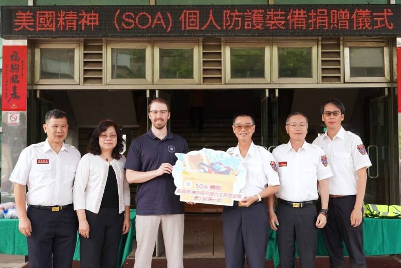 美國非政府組織SOA（Spirit of America）29日捐贈嘉義縣20個社區緊急應變隊，價值新台幣55萬元的個人防護及救援裝備，由嘉義縣消防局長蔡建安（右3）代表接受。左3為SOA台灣代表Lucas Wuebben。（嘉義縣消防局提供）